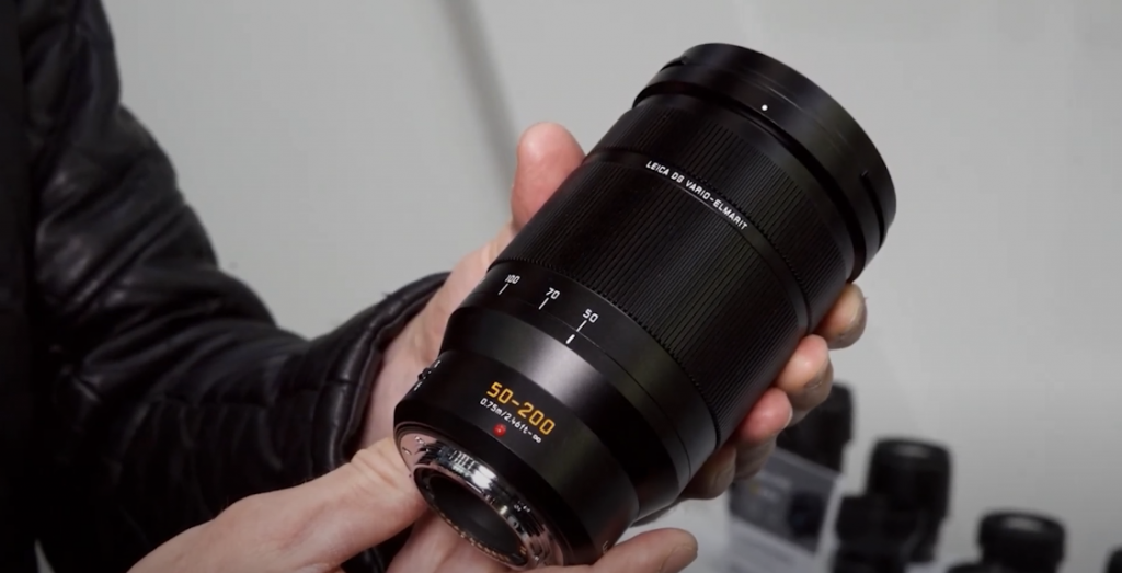 Hand holding a black camera lens, showing the details