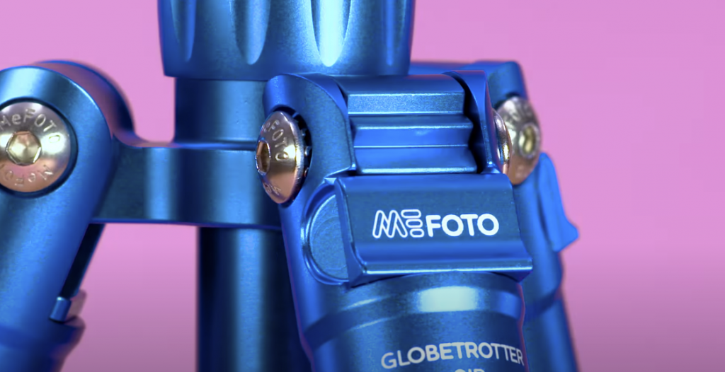 Close-up photo of a blue MeFOTO Backpacker Air tripod showcasing the brand name, against a pink background