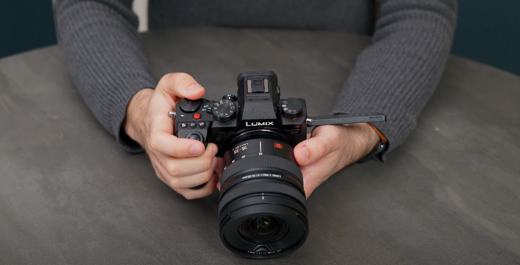 Hand holding a camera with a large lens