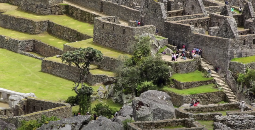 Scenic view of rock structures, buildings, and stairs surrounded by abundant grassy areas