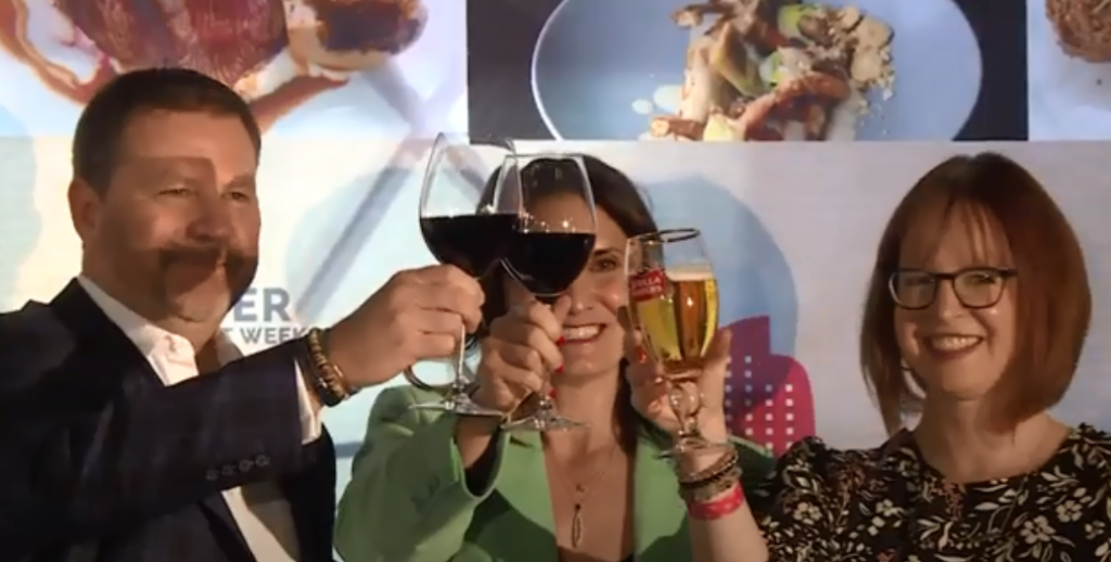 A man and a woman holding wine glasses, with a collage of various Denver Restaurant Week dishes in the background