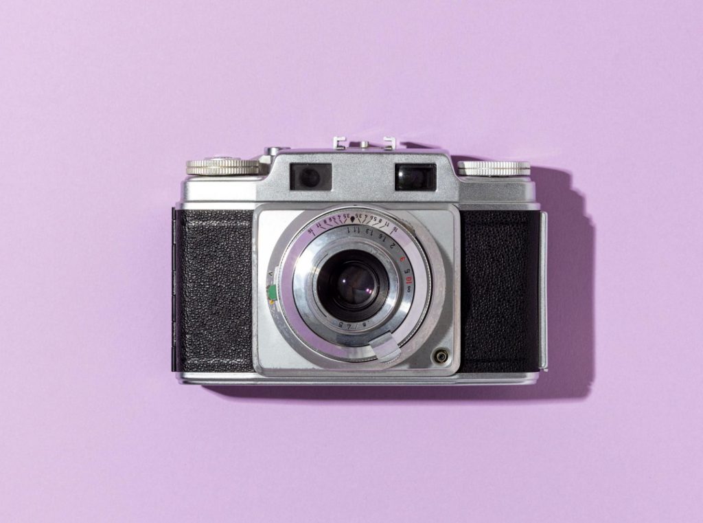 An analog camera on a purple background