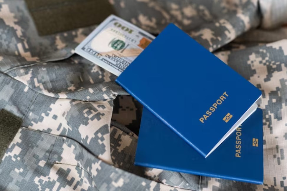 two passports and 100 dollar bills on a military uniform with pixeled camouflage