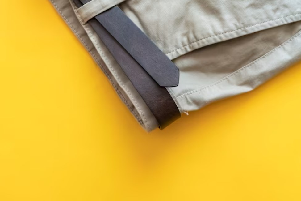 casual bottoms with a brown leather belt isolated on a yellow background