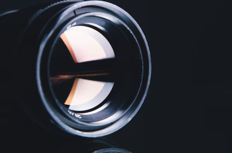 a close-up shot of an optical element with light reflections on a black background