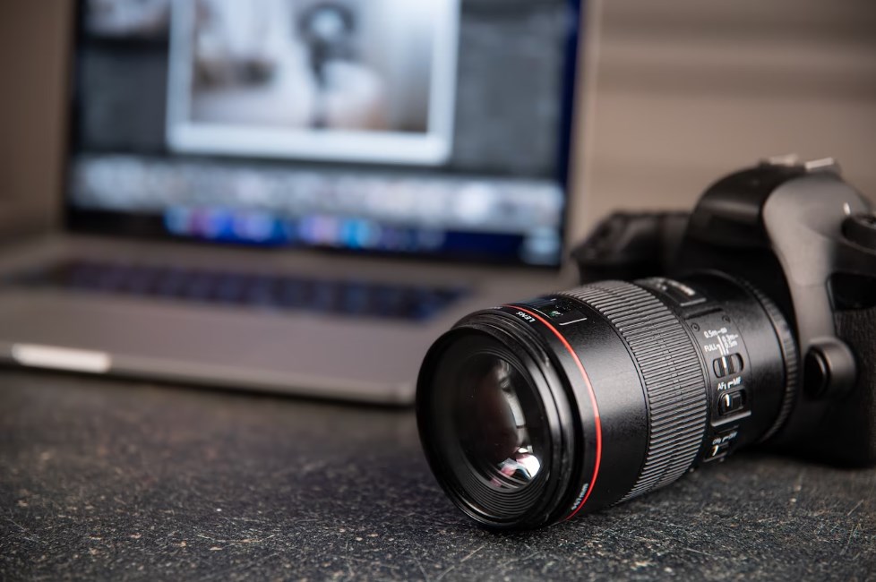 a professional Canon camera with a blurred laptop in the background