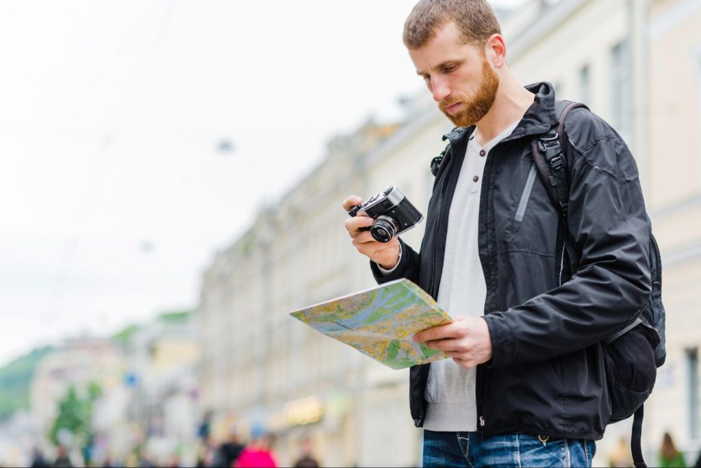 A tourist with a camera and a map in the middle of the street